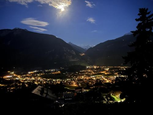 a view of a city at night with mountains at Hotel Bellevue in Sierre