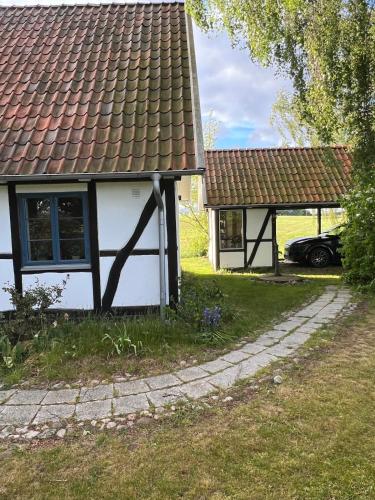 a white house with a brown roof and a car at Half-timbered house in Österlen in Sjöbo