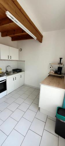 Il comprend une cuisine avec des placards blancs et du carrelage blanc. dans l'établissement Le Duplex Charentais, à Saint-Jean-dʼAngély