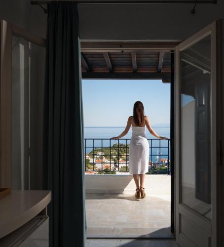 a woman in a white dress standing on a balcony at Atrium of Alonissos in Patitiri