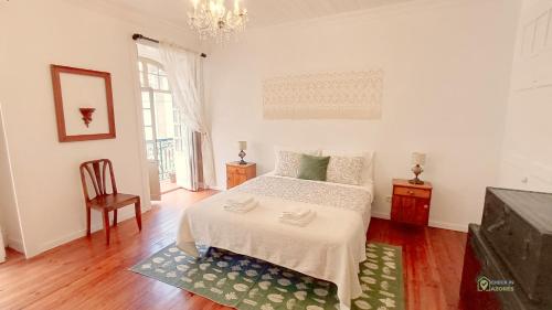 a white bedroom with a bed and a chandelier at Apartamento acolhedor no coração da cidade in Angra do Heroísmo