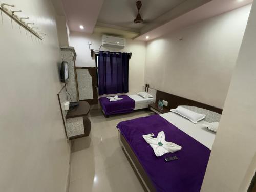 a small room with a purple bed and a purple blanket at Hotel Temple Sai in Shirdi