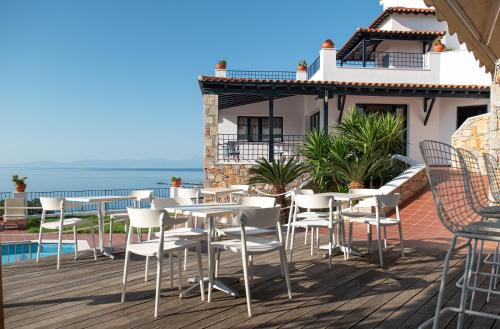a patio with tables and chairs and the ocean at Atrium of Alonissos in Patitiri