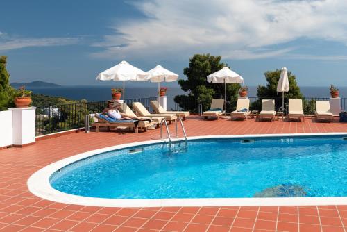 a person sitting in a chair next to a swimming pool at Atrium of Alonissos in Patitiri