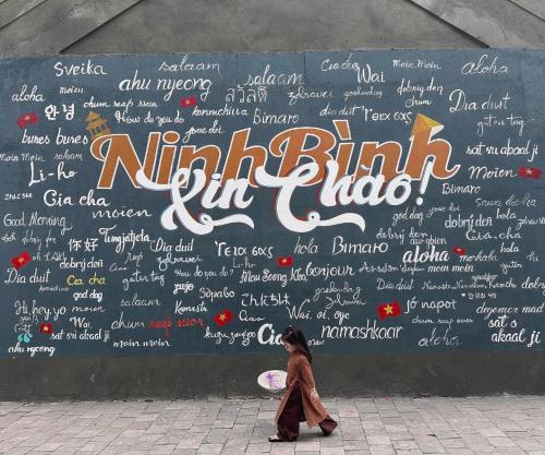 a woman walking past a wall with writing on it at The Horizon Hotel in Ða Gia