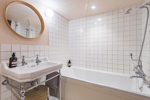 a bathroom with a sink and a tub and a mirror at Bertie's Cottage by Keepers Cottages in Robertsbridge