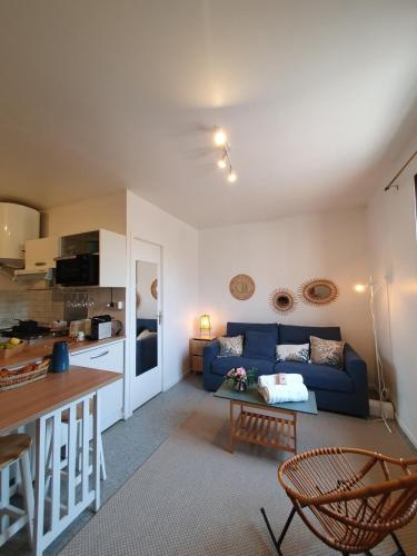 un salon avec un canapé bleu et une cuisine dans l'établissement Studio chaleureux proche métro B, à Pierre-Bénite