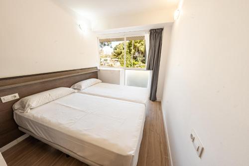 a small bedroom with two beds and a window at Park Suites Family Rentalmar in Salou