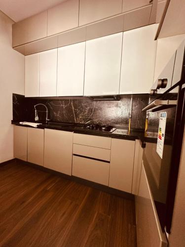 a kitchen with white cabinets and a wooden floor at luxueux S2 a Jardin de Carthage in Sidi Daoud