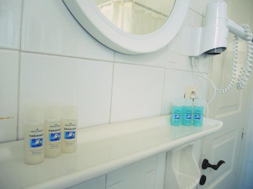 a bathroom with a mirror and toiletries on a shelf at Utopia Hotel Apartments in Agia Marina