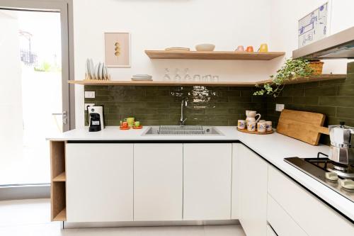 a kitchen with white cabinets and a sink at Salenthea apartments in Melpignano