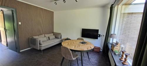 a living room with a table and a couch at Bungalow Hartje Veluwe in Otterlo