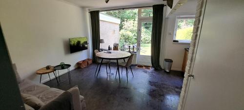 a living room with a table and chairs and a window at Bungalow Hartje Veluwe in Otterlo