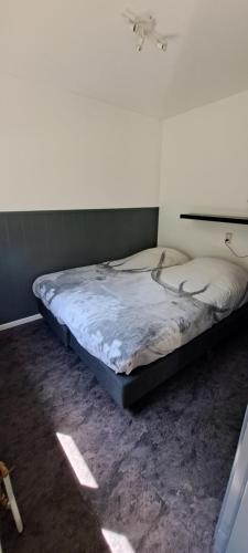 a bed sitting in a room with a wall at Bungalow Hartje Veluwe in Otterlo