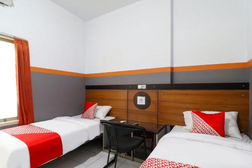 una camera con tre letti con cuscini rossi e bianchi di Hotel O Garut near Alun-Alun Tarogong formerly Wisma Etiga a Garut