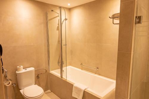 a bathroom with a shower and a toilet and a tub at Majestic City Retreat Hotel in Dubai