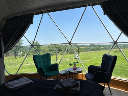 a room with two chairs and a bed and a window at Glamp Delux Ojcowski Park Narodowy in Wola Kalinowska