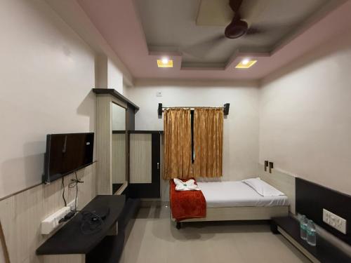 a small room with a bed and a sink at Hotel Temple Sai in Shirdi