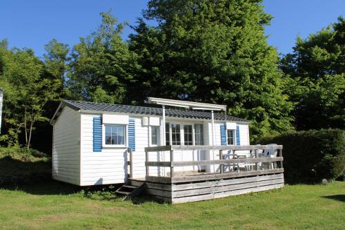 a small white shed with a porch in a field at Camping Le Balcon de Chartreuse in Miribel-les-Échelles
