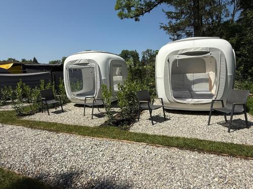 two rvs are parked in a yard with chairs at Direkt am Wallersee - Cubes - SELF CHECK-IN in Henndorf am Wallersee