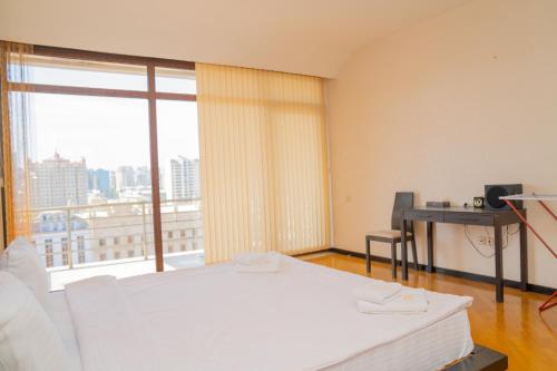 a bedroom with a white bed and a large window at Sunday Hotel & Apartments in Baku