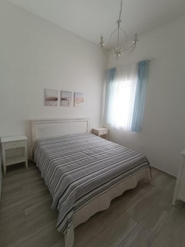 a white bedroom with a bed with a striped blanket at Chiaro di Luna - Appartamento Luna Crescente in Paestum