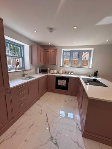a kitchen with brown cabinets and a marble floor at 2 High Silver House in Holt