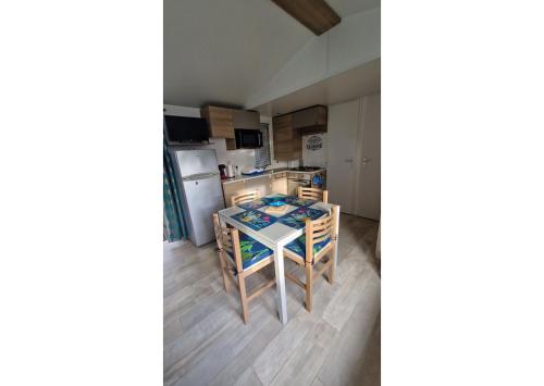 une cuisine avec une table et des chaises dans une pièce dans l'établissement Mobil-home Clim, TV, LL Camping LA CARABASSE 4 étoiles - MH-A012, à Vias