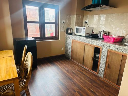 a kitchen with a table and a counter with a microwave at Yogi's Heritage in Patan - Heritage Family Studio in Pātan