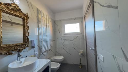 a bathroom with a sink and a mirror and a toilet at B&B Antenna 2 by Ca-Sa Check in Chioggia