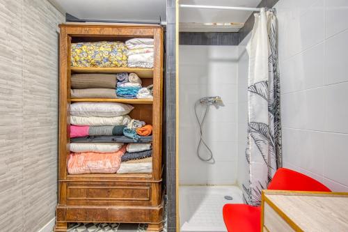 La salle de bains est pourvue d'un placard en bois, de serviettes et d'une baignoire. dans l'établissement Dari, à Bordeaux