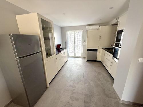 une cuisine avec des armoires blanches et un réfrigérateur en acier inoxydable dans l'établissement Villa des Salins à Hyères, à Hyères