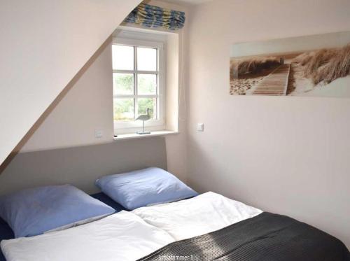 a bed with blue pillows in a room with a window at Leo-s-Hues in Tinnum