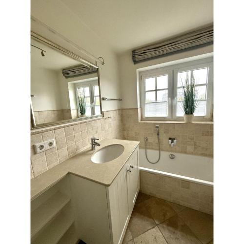 a bathroom with a sink and a tub and a mirror at Leo-s-Hues in Tinnum