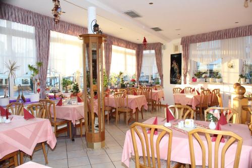 ein Restaurant mit rosa Tischen, Stühlen und Fenstern in der Unterkunft Hotel- Restaurant Zum Kleinen König in Bad Zwesten