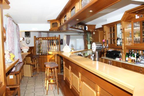 a kitchen with wooden cabinets and a bar with stools at Hotel- Restaurant Zum Kleinen König in Bad Zwesten