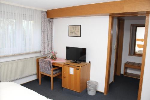 a room with a desk with a television and a bed at Hotel- Restaurant Zum Kleinen König in Bad Zwesten