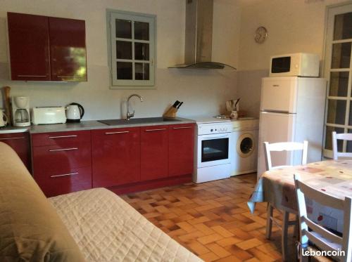 une cuisine avec des armoires rouges et un réfrigérateur blanc dans l'établissement le pigeonnier, à La Celle-sous-Gouzon