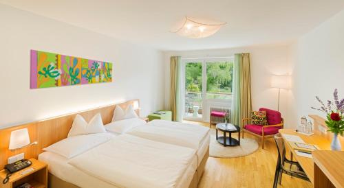 a hotel room with a white bed and a desk at At the Park Hotel in Baden