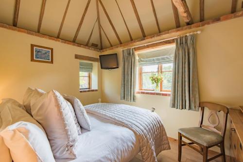 a bedroom with a bed and a chair and a window at Pond Cottage by Keepers Cottages in Egerton