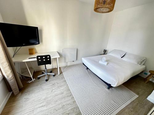 une chambre avec un lit, un bureau et une télévision dans l'établissement Studio cosy sur cour, à Poitiers