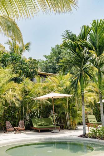 a pool with chairs and an umbrella and palm trees at Soul Spring Sanctuary Cuernavaca in Xochitepec