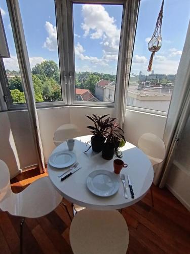une table et des chaises blanches dans une chambre avec fenêtres dans l'établissement Cosy et spacieux - Caluire et cuire, à Caluire-et-Cuire