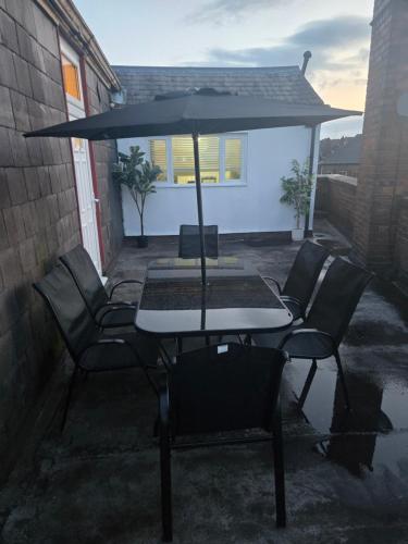 a table and chairs with an umbrella on a patio at Glamorous and stylish in Wolverhampton