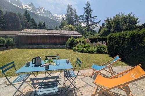 - une table et des chaises dans une cour avec des montagnes dans l'établissement Appartement Sérénité - Welkeys, à Chamonix-Mont-Blanc