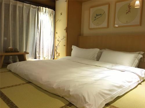 a large white bed in a bedroom with a window at Water Hotel, Pingyao in Pingyao