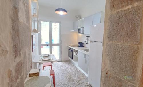 a kitchen with a white refrigerator and a table and chairs at Apartamento acolhedor no coração da cidade in Angra do Heroísmo