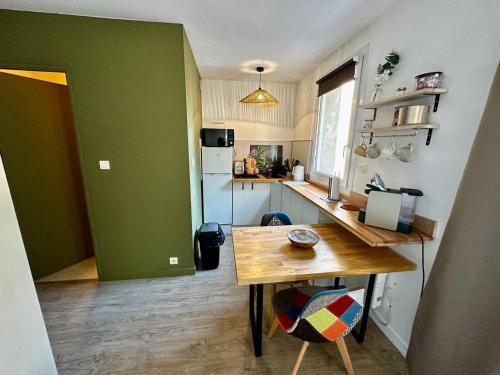 - une cuisine avec une table en bois et un mur vert dans l'établissement Studio cosy sur cour, à Poitiers