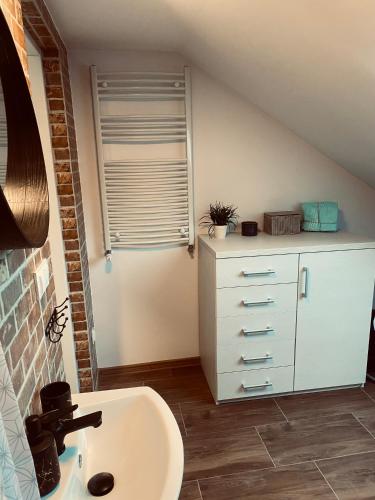 łazienka z umywalką i białą komodą w obiekcie Apartament Turkusowy w mieście Puck