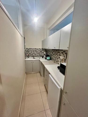 a white kitchen with white cabinets and a window at AKTIS apartment 4 near airport in Artemida